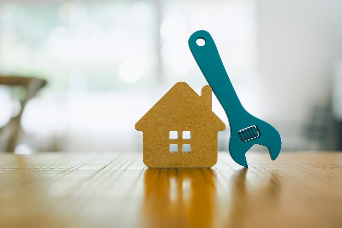 Herramientas y llave sobre maqueta de vivienda para servicios de instalaciones